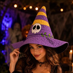 May include: A quilted witch hat featuring alternating purple and yellow horizontal stripes on the cone. The hat displays a white skull applique with black eye sockets, a green embroidered vine, and black stitched cross-hatch detailing.