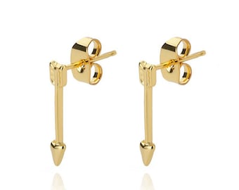 May include: A pair of gold-colored arrow stud earrings. Each earring features a long, slender shaft with a pointed tip and a small, square-shaped detail at the top. The earrings are designed with a post and butterfly backing.