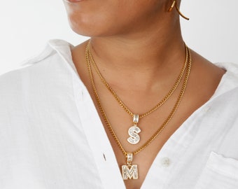May include: Two gold chain necklaces with a diamond encrusted letter 'S' pendant and a diamond encrusted letter 'M' pendant.