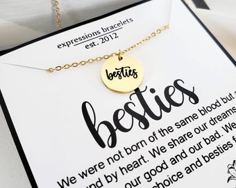 May include: A gold-colored necklace with a circular pendant that reads "besties" in a cursive font. The necklace is displayed on a white card with the word "besties" in large letters and the text "expressions bracelets est. 2012".