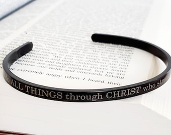 May include: A black metal bracelet with the inscription "I do ALL THINGS through CHRIST who strengthens me".