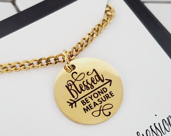 May include: Gold chain necklace with a round pendant that says "Blessed Beyond Measure" with an arrow pointing to the right. The pendant has a small infinity symbol at the bottom.