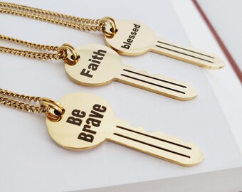 May include: Three gold key-shaped necklaces with the words "Faith", "Be Brave", and "Blessed" engraved on the keyheads.