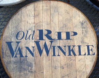 May include: A wooden barrel top with the words "Old Rip Van Winkle" printed in black paint.