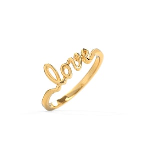 Puede incluir: Un anillo de oro pulido que presenta la palabra love escrita en una letra cursiva continua. El metal tiene una superficie lisa y reflectante que capta la luz, formando una banda delicada que se curva para crear las letras de la palabra.