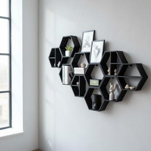 K&ouml;nnte beinhalten: Ein modulares Wandregalsystem bestehend aus mehreren miteinander verbundenen schwarzen sechseckigen Rahmen. Die Regale sind in einem Wabenmuster angeordnet und enthalten verschiedene Dekorationsgegenst&auml;nde wie B&uuml;cher, Bilderrahmen, Skulpturen und Pflanzen.