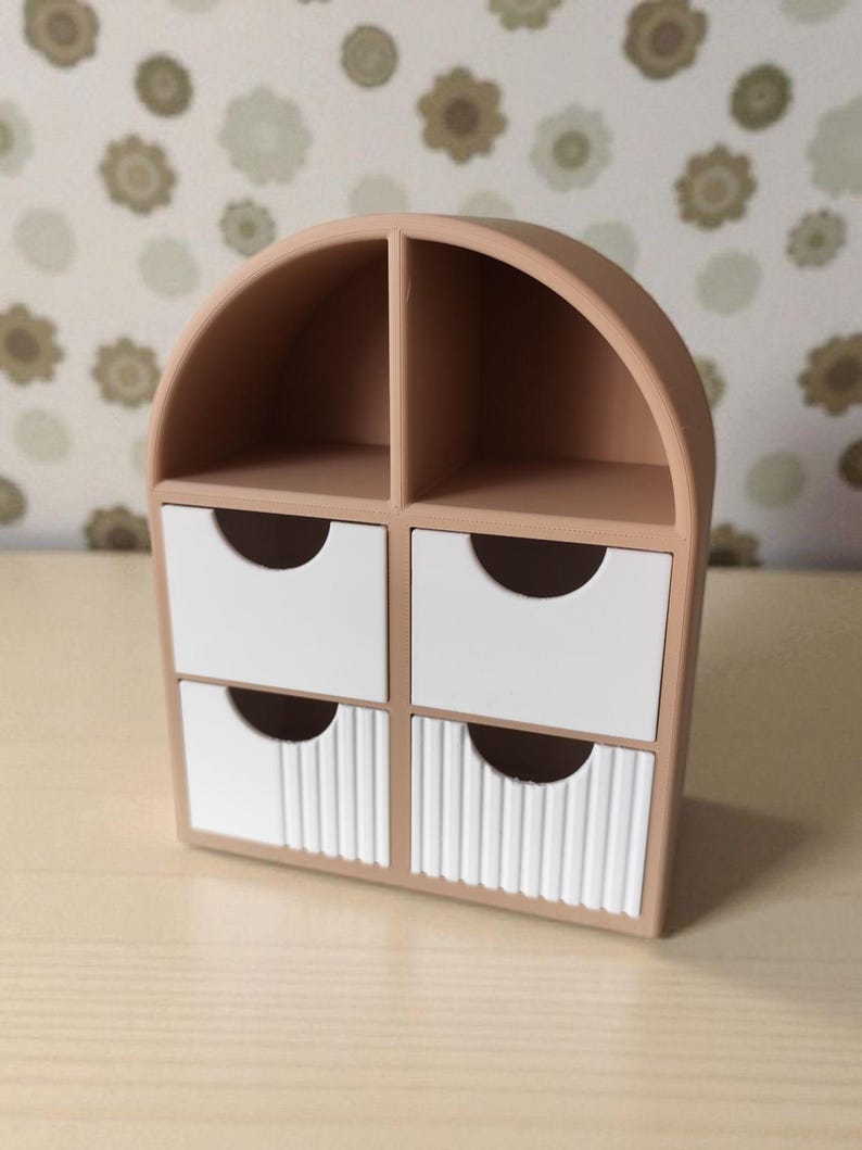 May include: A small, arched, light brown storage organizer featuring two open top compartments and four drawers. The two top drawers are smooth white, while the two bottom drawers feature a vertical ribbed texture, each with a semi-circular cutout.