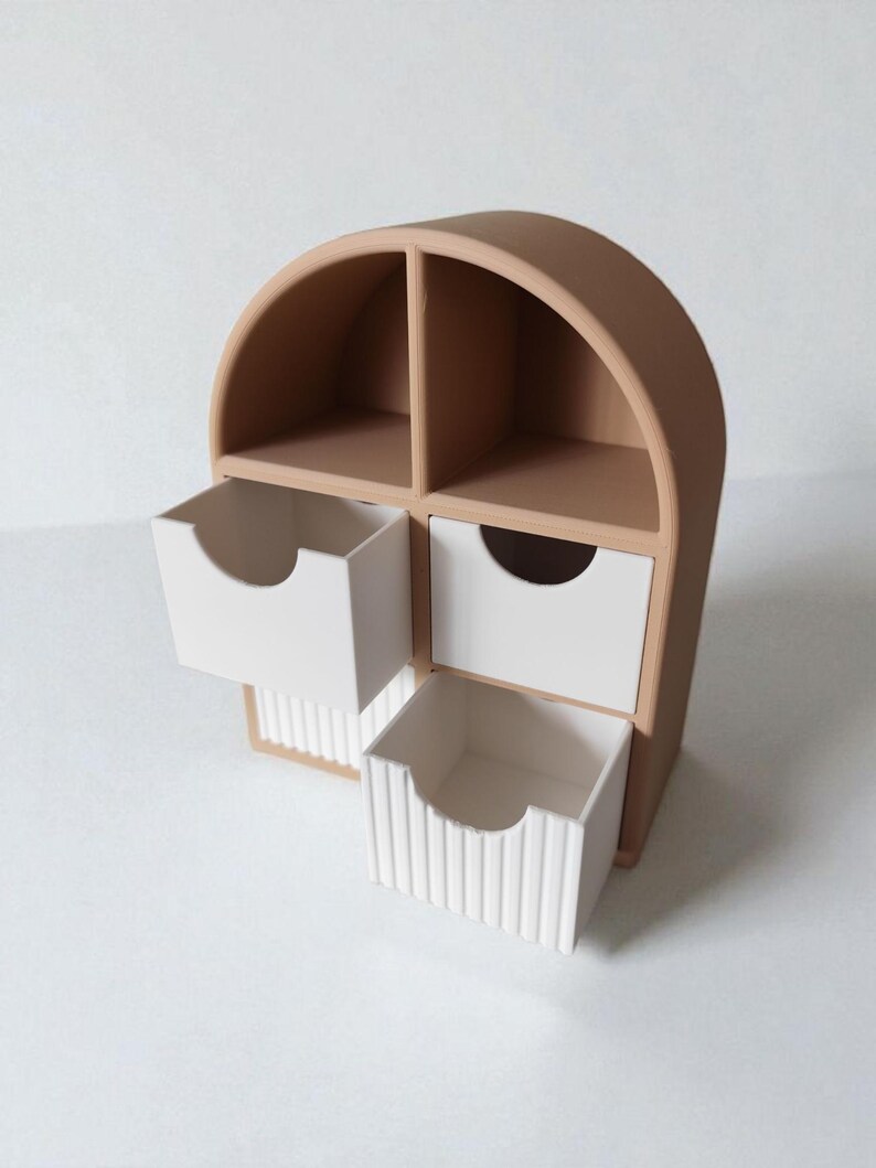 May include: A tan arched desktop organizer featuring two open upper compartments and two white drawers. The bottom drawer has a vertical ribbed texture on its front, while both drawers feature a semi-circular cutout for easy opening and access.