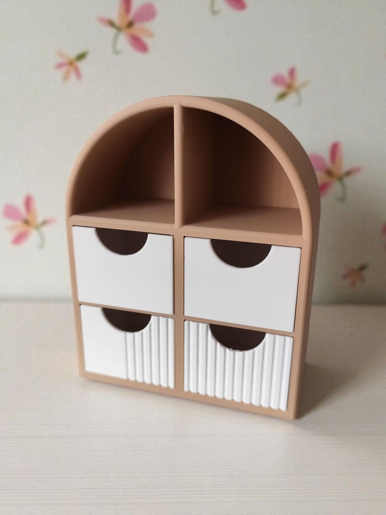 May include: A beige desktop organizer with an arched top, featuring two open upper compartments and four lower drawers. The two bottom drawers have a vertical ribbed texture on their front panels, while all four drawers have semi-circular cutouts.