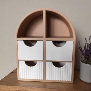 May include: A beige arched desktop organizer featuring two open top compartments and four drawers. The two upper drawers have smooth white fronts, while the two lower drawers feature a vertical ribbed texture on their white faces.