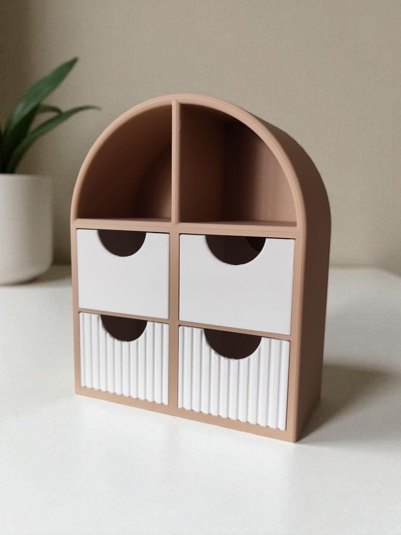 May include: A desktop organizer with a tan arched frame featuring two open top compartments and four drawers. The top two drawers are smooth white, while the bottom two drawers feature a vertical ribbed texture, each with a semi-circular cutout.
