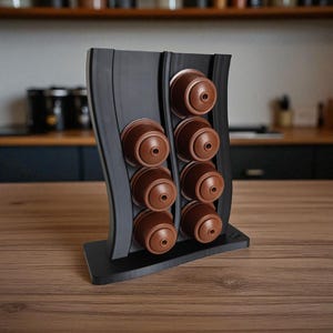 Puede incluir: Un soporte vertical negro para c&aacute;psulas de caf&eacute; con dise&ntilde;o ondulado, que cuenta con dos columnas para un total de ocho c&aacute;psulas de caf&eacute; marrones. El soporte tiene una base plana y est&aacute; fabricado con un acabado mate liso para organizar c&aacute;psulas.
