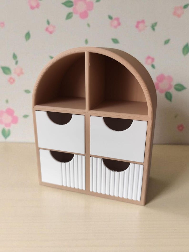 May include: A beige desktop organizer with an arched top, featuring two open upper compartments and four lower drawers. The two top drawers have smooth white fronts, while the two bottom drawers feature a vertical ribbed texture on the white fronts.