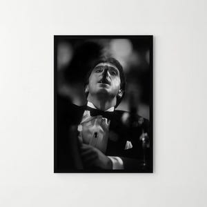 May include: A black and white framed photograph depicting a person in a formal tuxedo with a bow tie and white pocket square, looking upward with an open mouth. The image features high-contrast lighting, creating deep shadows and bright highlights.