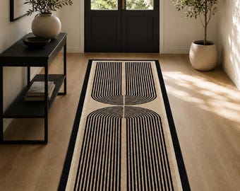 Puede incluir: Una alfombra de pasillo rectangular con fondo beige y un llamativo patrón geométrico negro de dos arcos espejados compuestos por líneas verticales paralelas. La alfombra tiene un borde negro sólido sobre un suelo de madera.