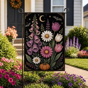 May include: A rectangular garden flag featuring a black background with a botanical illustration of purple foxgloves, white and pink daisies, and tulips. An orange pumpkin sits at the base, while a crescent moon and bats decorate the top.