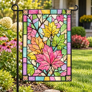 May include: A rectangular garden flag featuring a stained glass style design of colorful maple leaves in shades of pink, yellow, orange, and green. The border consists of small rectangular tiles in various colors with a small maple leaf in each corner.