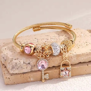 Pulsera dorada con dijes para mujer, brazalete con llave y candado de cristal rosa, pulsera de cable de acero inoxidable, elegante regalo de joyería con dijes para ella.