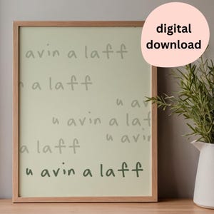 May include: A framed wall art print featuring a light green background with the repeated text 'u avin a laff' in varying shades of green, with the bottom line in the darkest green font. The frame is made of light-colored wood.