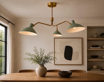 May include: A three-light chandelier featuring a central brass-toned rod and horizontal arms extending to three sage green dome-shaped shades. The fixture is suspended from a circular brass ceiling canopy, with each shade pointing downward.