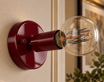 May include: A wall-mounted light fixture featuring a glossy, deep red circular base and a matching cylindrical socket. A large, clear, spherical glass light bulb with visible internal filaments is screwed into the socket.