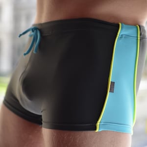 May include: Black swimming trunks with a turquoise and yellow stripe down the side.