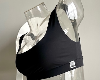 Könnte beinhalten: Schwarzer Sport-BH mit Rundhalsausschnitt und Racerback-Design. Der BH hat ein kleines Logo unten rechts, auf dem "SHUPE" steht.