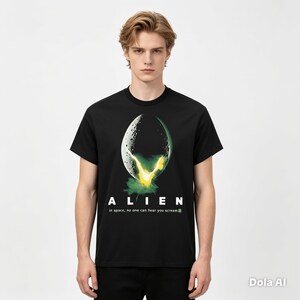 May include: A black short-sleeved t-shirt featuring a graphic of a cracked egg emitting a bright yellow and green glow. Below the graphic, the text reads ALIEN and in space, no one can hear you scream in white, sans-serif lettering.