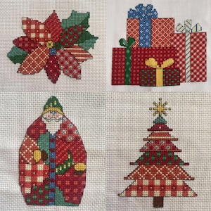 May include: Four cross-stitch designs on white fabric. A poinsettia with red and green patterned petals, a stack of wrapped gifts with bows, a Santa Claus figure, and a Christmas tree with a star.