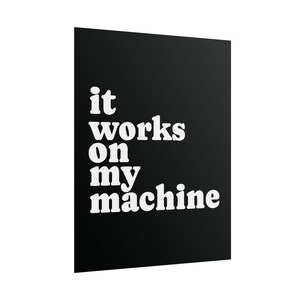 May include: A rectangular black wall art print featuring the white text "it works on my machine" in a bold, rounded sans-serif font. The design is centered on the black background, creating a high-contrast visual display for a wall or desk.