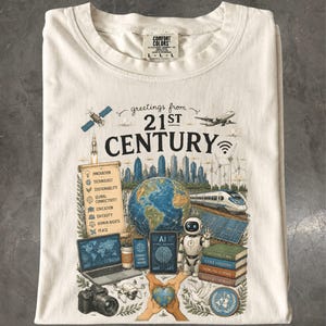Könnte beinhalten: Ein cremefarbenes T-Shirt mit einem Grafikdruck und dem Text "greetings from 21ST CENTURY". Das Design zeigt einen Globus, einen Roboter, einen Laptop, eine Kamera, einen Zug, Windkraftanlagen, einen Satelliten, ein Flugzeug und eine Schriftrolle.