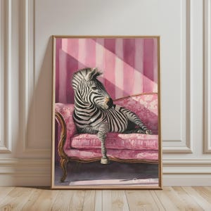 May include: A framed wall art print featuring a black and white zebra resting on a pink floral patterned chaise lounge. The background consists of vertical pink stripes with diagonal light beams casting shadows across the scene.