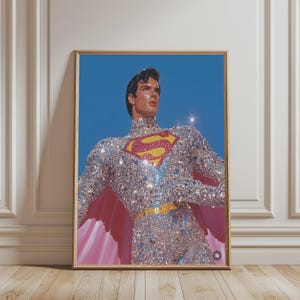 Può includere: Una stampa artistica incorniciata raffigurante una figura simile a Superman che indossa una tuta a collo alto e maniche lunghe ricoperta di paillettes argentate. Il petto mostra un emblema a forma di S di colore giallo e rosso.