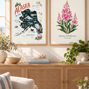 May include: Two framed wall art prints in light wood frames. The left print is a map of Alaska featuring illustrations of wildlife, landmarks, and the text ALASKA. The right print depicts a pink Fireweed flower with the text Alaska Wildflower Fireweed.