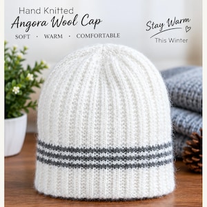 Peut inclure: Un bonnet en laine angora tricoté à la main de couleur blanche avec une texture côtelée et trois rayures horizontales grises près du bord inférieur. Le texte sur l'image indique : Hand Knitted Angora Wool Cap, SOFT, WARM, COMFORTABLE, Stay Warm This Winter.