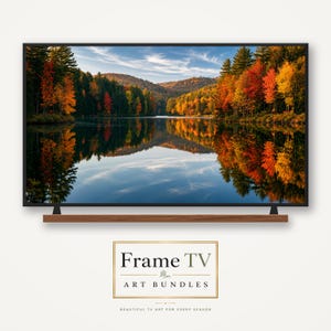 May include: A television screen displaying a landscape photograph of a lake surrounded by autumn trees with red, orange, and yellow foliage, reflecting in the water. Below the screen is a wooden shelf. Text reads Frame TV ART BUNDLES.