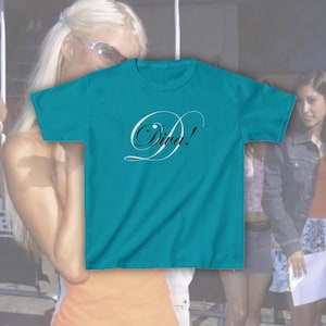 Peut inclure: Un t-shirt à manches courtes de couleur bleu sarcelle avec le mot Diva! imprimé en grandes lettres blanches en écriture cursive au centre de la poitrine. Le vêtement présente une encolure ronde et un ourlet droit en tissu uni.