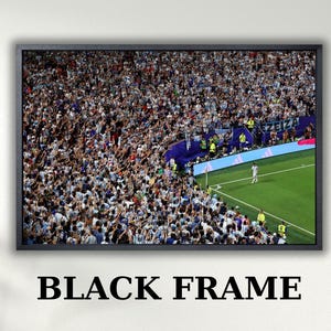 May include: A rectangular wall art piece featuring a black frame surrounding a photograph of a crowded soccer stadium. The image captures a dense crowd of spectators in the stands, with a green grass field and a single player visible in the corner.