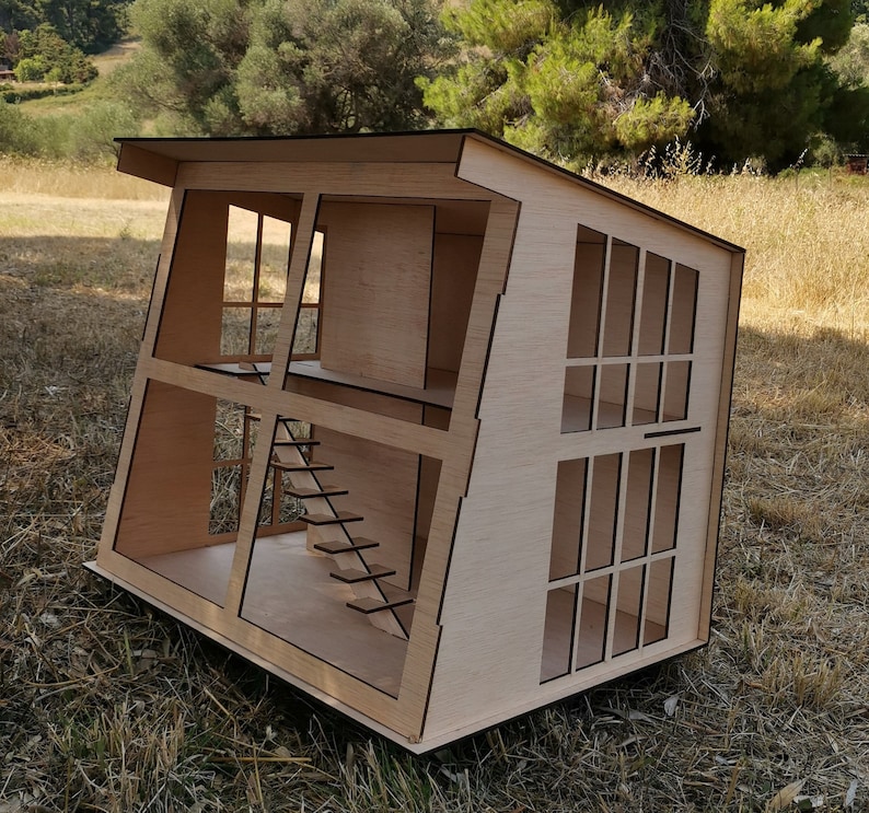 K&ouml;nnte beinhalten: Ein Holzmodell eines Puppenhauses mit einem schr&auml;gen Dach und mehreren Fenstern. Das Puppenhaus ist aus hellbraunem Holz gefertigt und hat eine Treppe im Inneren.