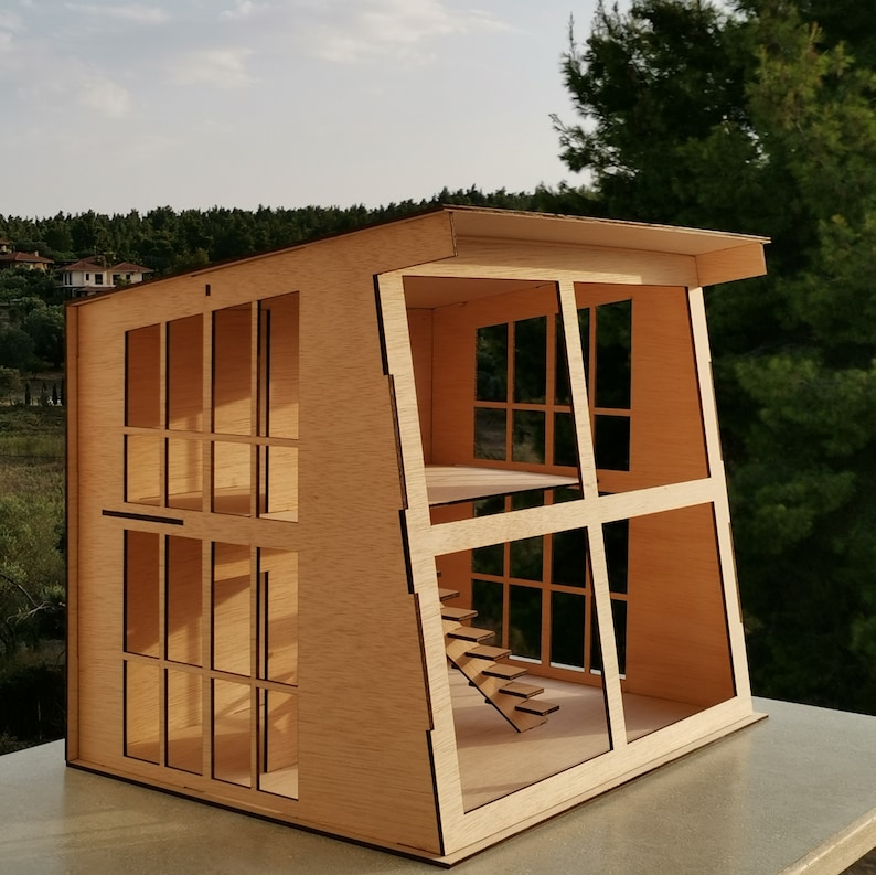 K&ouml;nnte beinhalten: Ein Holzmodell eines Hauses mit einem schr&auml;gen Dach und gro&szlig;en Fenstern. Das Haus hat eine Treppe, die zu einer oberen Ebene f&uuml;hrt. Das Modell ist aus hellbraunem Holz gefertigt und hat eine nat&uuml;rliche Holzoptik.