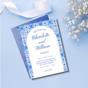 May include: A rectangular wedding welcome sign featuring a white center with an arched top, framed by a blue and white floral tile pattern. The text reads: WELCOME TO Charlotte and William WEDDING. Thank you for joining us on this special day as we begin our next chapter together. May 9, 2026.