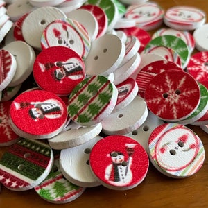 May include: A collection of round wooden buttons with various Christmas-themed designs. The buttons feature red and green colors with images of snowmen, snowflakes, and winter patterns.