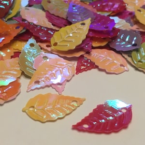 May include: Assortment of iridescent leaf-shaped sequins in various colors, including pink, orange, yellow, green, purple, and red.