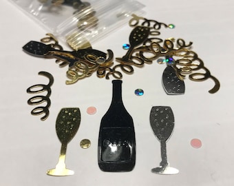 May include: Assortment of gold and silver confetti featuring champagne bottles, glasses, and swirls. The confetti is on a white background.