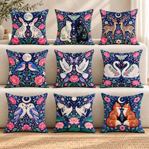 Puede incluir: Un conjunto de nueve cojines cuadrados con fondos azul oscuro y parejas de animales simétricas, incluyendo conejos, gatos, ciervos, pájaros azules, palomas, cisnes, búhos, grullas y zorros, rodeados de coloridos patrones florales y lunas.