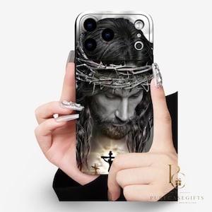 Op de afbeelding: Een zwart-wit smartphonehoesje met een gedetailleerd portret van een figuur met een doornenkroon. Onder het portret verlicht een helder schijnsel de silhouetten van drie kruisen. Het ontwerp bedekt de achterkant van het mobiele apparaat.