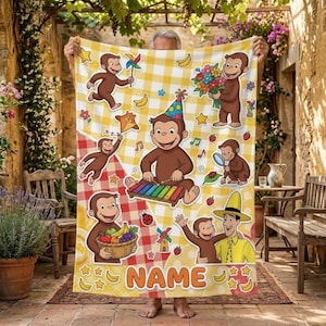 Può includere: Una coperta in pile a quadri gialli e bianchi con illustrazioni di Curious George, tra cui la scimmia che suona lo xilofono, tiene un cesto di frutta e con l'Uomo col Cappello Giallo. La parola NAME è stampata in basso.