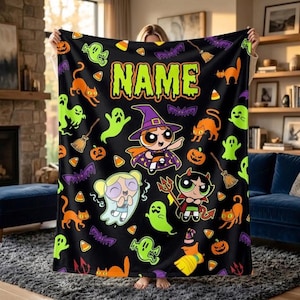 May include: A black fleece blanket featuring a repeating Halloween pattern of orange cats, green ghosts, purple bats, pumpkins, and candy corn. The center displays three cartoon characters in costumes with the word NAME printed in lime green text.
