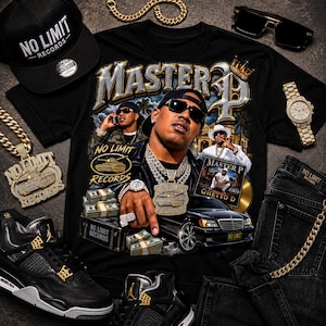 Peut inclure: Un t-shirt noir avec une impression graphique de Master P, un char, des liasses de billets, une voiture de luxe noire et le texte "MASTER P" et "NO LIMIT RECORDS". Le t-shirt est entouré d'une casquette noire, de chaînes dorées, d'une montre, de lunettes de soleil et d'un jean noir.
