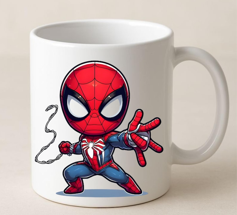 Puede incluir: Una taza de cer&aacute;mica blanca con una ilustraci&oacute;n gr&aacute;fica de un superh&eacute;roe estilo chibi, vestido con un traje rojo y azul con un emblema de ara&ntilde;a blanco en el pecho, en una postura din&aacute;mica con una mano extendida y una telara&ntilde;a detr&aacute;s.